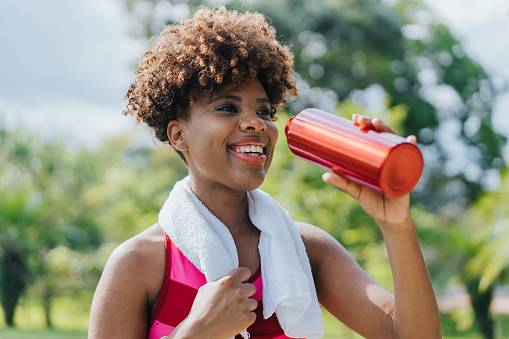 Portrait of a young athlete woman drinking water during exercise