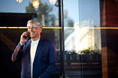 Cheerful businessman using mobile phone at office