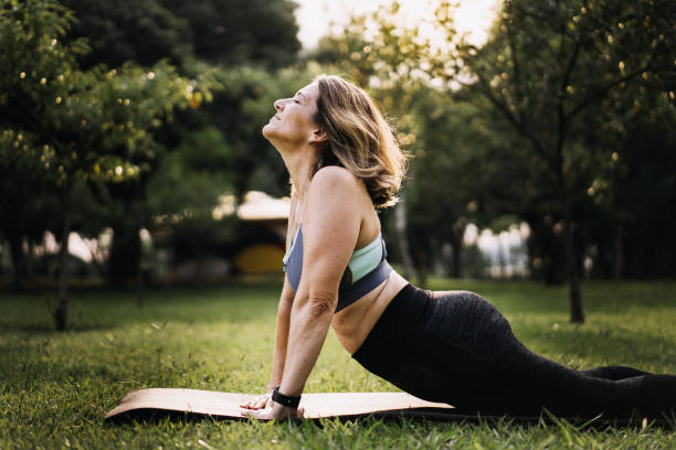 mulher praticando exercício físico em esteira em parque público - healthy lifestyle yoga vitality flexibility - fotografias e filmes do acervo