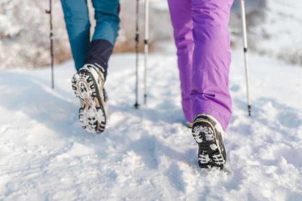 Close-up of two hikers' boots while walking in the snow.