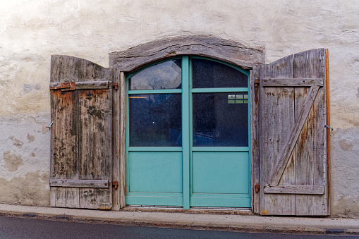 Metal ornaments and hinges on two brown wooden church doors.