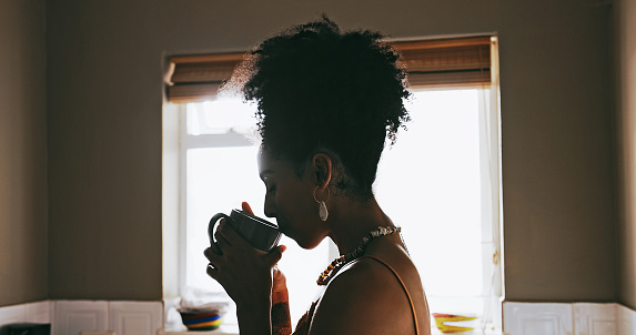 Coffee, thinking and black woman relax in kitchen for calm, peaceful and happiness in morning. Reflection, happy mindset and girl drinking hot beverage or tea for wellness, mindfulness and motivation