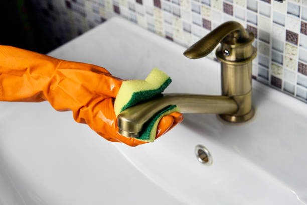 Improper care of brass water faucet, housekeeper wipes tap with abrasive side of washing sponge. Incorrect maintenance of brass water tap, maid wipes faucet with abrasive side of washing sponge. water sanitation worker washing faucet stock pictures, royalty-free photos & images