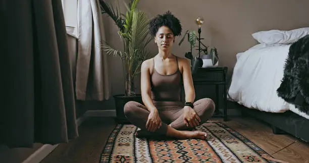 Photo of Zen, relax and mediation with black woman and yoga in bedroom for calm, peace and morning routine. Wellness, breathing and balance with health girl training at home for spiritual, healing and energy