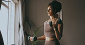 Dumbbell exercise, black woman and workout in home, bedroom and apartment for strong body, muscle and wellness. Young female person, sports fitness and weights in house for power, training and focus