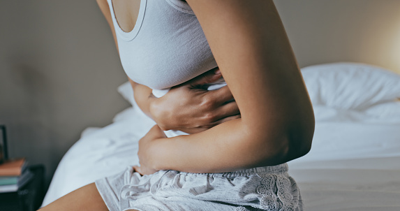 Menstruation, sick and stomach ache with black woman in bedroom for indigestion, cramps and illness. Frustrated, gas and stress with girl on bed for constipation, bloating and intestine problems