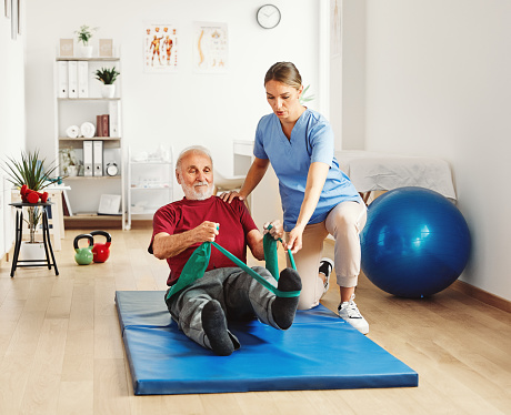 Doctor or nurse caregiver exercise with senior man at clinic or nursing home