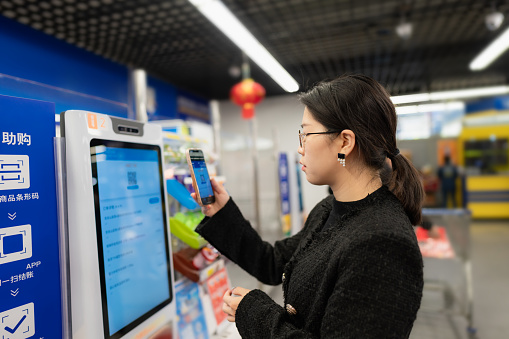 Beautiful asian woman pay shopping bill using mobile phone