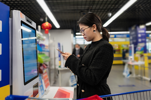 Beautiful asian woman pay shopping bill using mobile phone