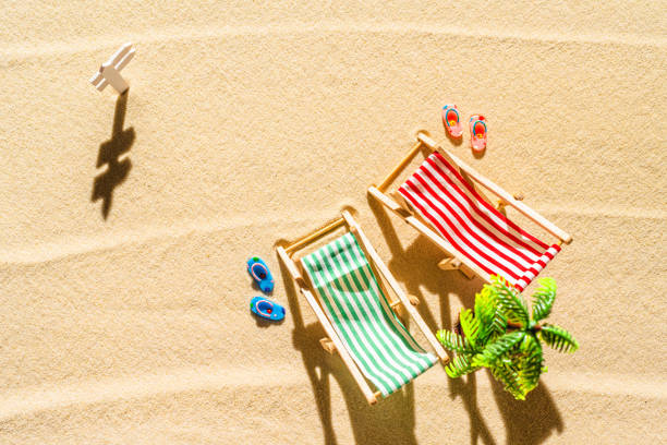 vue aérienne de deux chaises longues, transat, salon, tongs, palmier sur la plage de sable fin. concept d’été et de voyage. minimalisme - beach tropical climate palm tree deck chair photos et images de collection