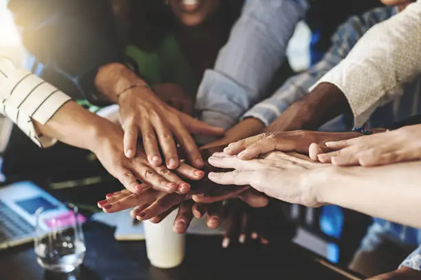 Photo of Multiracial group of businesspeople joining hands in stack - cooperation, unity, success and team building business concept