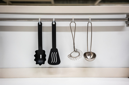 Set of cutlery or kitchen tools hanging on wall in the kitchen for display.