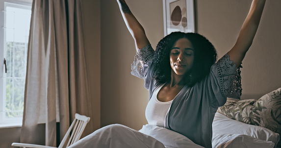 Wake up, stretching and black woman in bedroom, ready to start new day and sitting after sleeping. African American female, lady and in bed with peace, restful and stretch with sunlight and mindset