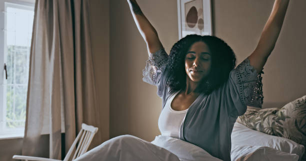 wake up, stretching and black woman in bedroom, ready to start new day and sitting after sleeping. african american female, lady and in bed with peace, restful and stretch with sunlight and mindset - wake up stretching women black imagens e fotografias de stock