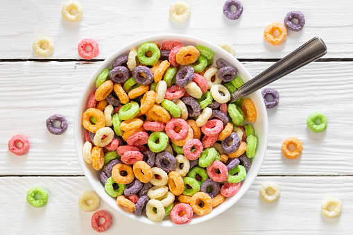 Colored breakfast cereals laid out in a bowl on a white wooden background, top view, children's healthy breakfast.