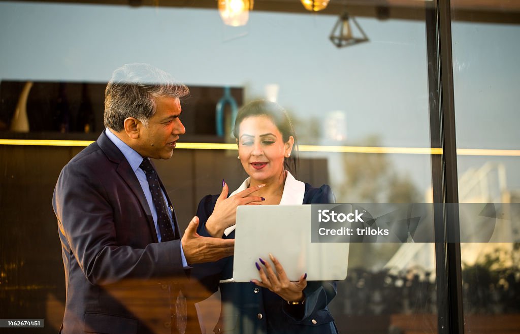 Business people with laptop at office Businessman and businesswoman working together using laptop at office India Stock Photo
