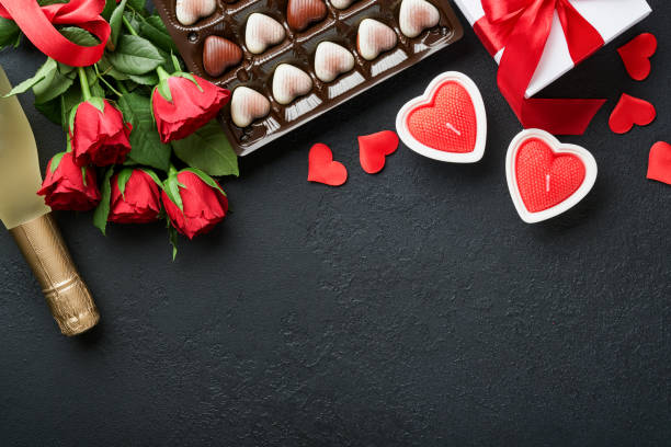 valentines day card. rose red flowers brownie cookies and chocolate candy on heart shaped, gift box with wine on black background. mothers or womens day greeting card. top view flat lay - valentine candy fotos imagens e fotografias de stock