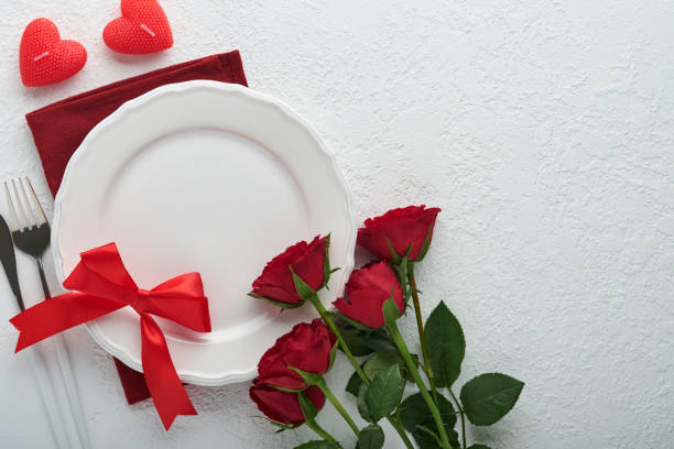 istock Valentines day romantic table setting. Empty or closeup of a dinner black plate, knife, fork and decorative silk hearts on white background. Holiday concept. Copy space for inscriptions. 1462678467