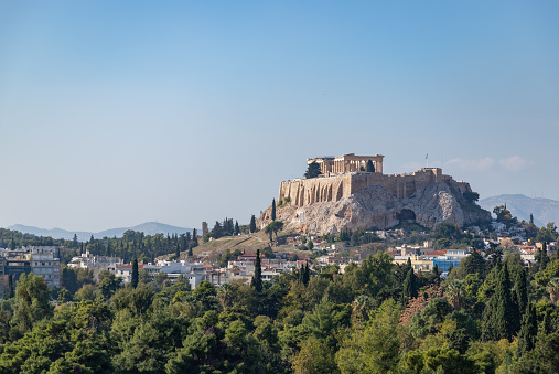 A picture of the Acropolis of Athens, and the Parthenon, as seen above a tree line in the foreground.
