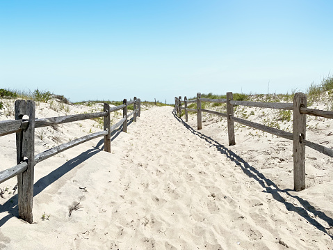 Weathered wooden fence along sandy path to beach