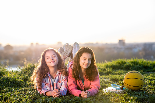 little girls are lying on the grass  on sunset