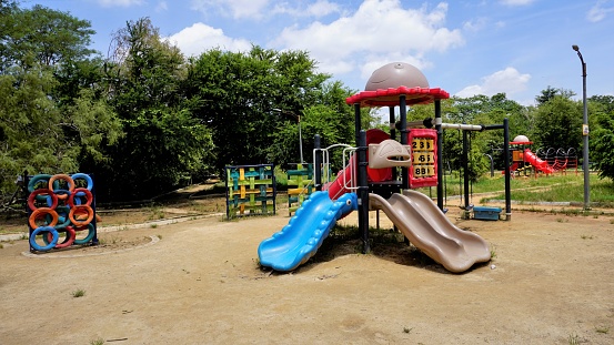 Cheerful parents having fun with their son in the playground. Little boy is sliding.   