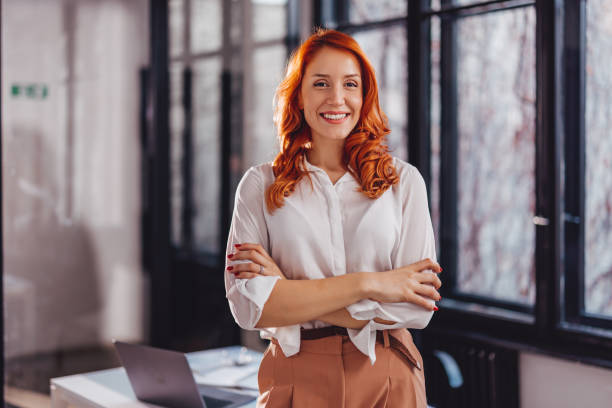 portrait of confident young businesswoman standing in office with arms crossed. - business women computer cheerful imagens e fotografias de stock