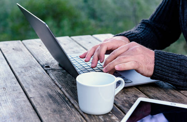 Close-ups of technology in use  and communication Remote man checks data from laptop while drinking coffee. laptop tablet and coffee cup standing on her desk para birimi stock pictures, royalty-free photos & images