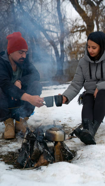 istock Couple drinking hot tea by campfire on snowy winter day 1462700225