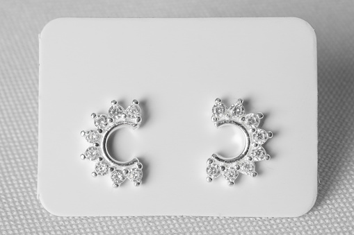Elegant silver earring jewelry with precious stones, on white background. Half moon.