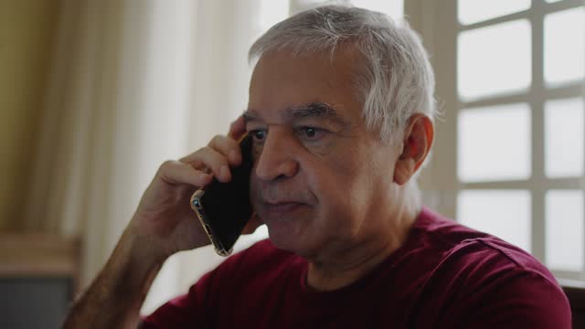 Senior man talking on the mobile phone at home