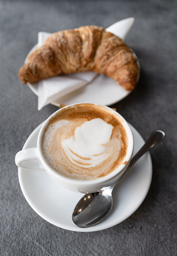 Café italiano: cornetto y capuchino en la cafetería photo