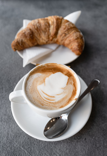 The real Italian cappuccino at bar, as served in Italy. A typical breakfast mix, a cornetto croissant pastry and a cappuccino