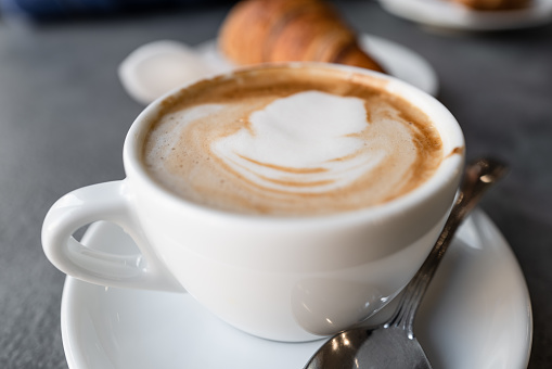 The real Italian cappuccino at bar, as served in Italy. A typical breakfast mix, a cornetto croissant pastry and a cappuccino