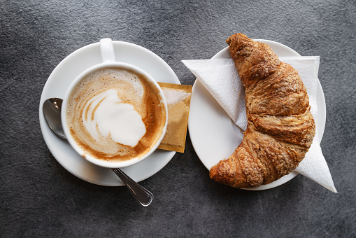 The real Italian cappuccino at bar, as served in Italy. A typical breakfast mix, a cornetto croissant pastry and a cappuccino