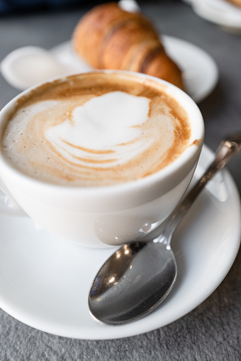 The real Italian cappuccino at bar, as served in Italy. A typical breakfast mix, a cornetto croissant pastry and a cappuccino