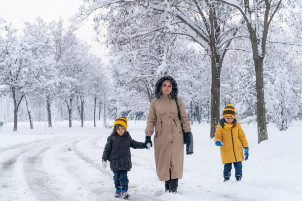istock mother and son walking together in public park under snow 1462714294