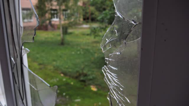 View outside through broken glass window. Large shards glass in broken window