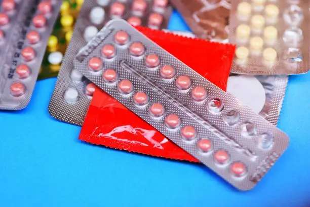 Photo of Contraception pills and condom on blue background - Birth control contraceptive means prevent pregnancy or sexually transmitted disease