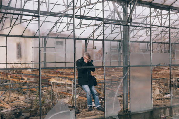 Desperate man at his ruined green house garden due to economic crisis