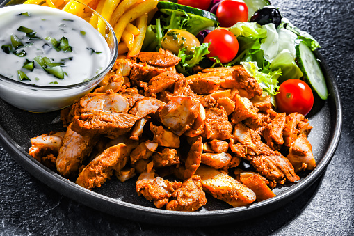 Kebab served with french fries, vegetable salad and tzatziki