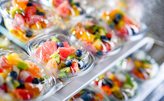 Plastic boxes with pre-packaged fruit salads, put up for sale in a commercial refrigerator