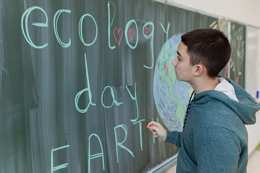 Young artist using colored chalks to draw a beautiful poster of planet Earth - Save the Planet campaign