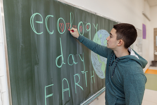 Young artist using colored chalks to draw a beautiful poster of planet Earth - Save the Planet campaign