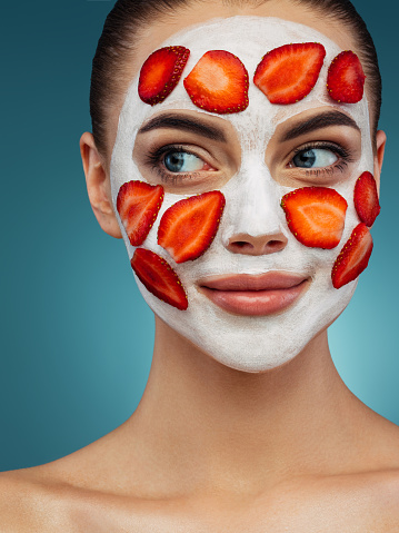 Feliz jovencita con máscara facial de fresa en su cara photo