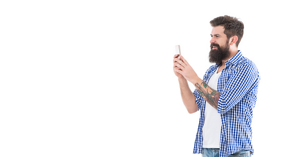 smiling brutal bearded man taking photo with phone isolated on white background with copy space.