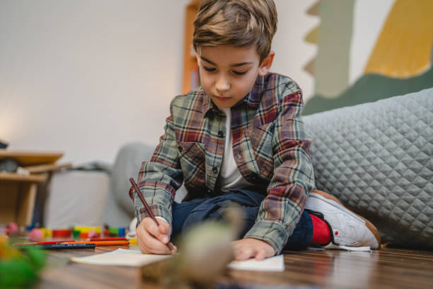 istock one small caucasian boy Gradeschooler child draw with crayon at home 1462752010