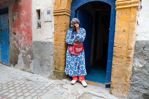 Marrakesh, Morocco - January 27, 2020: Street scene, a mature woman standing on the street and makes a telephone call, Marrakesh, Morocco.