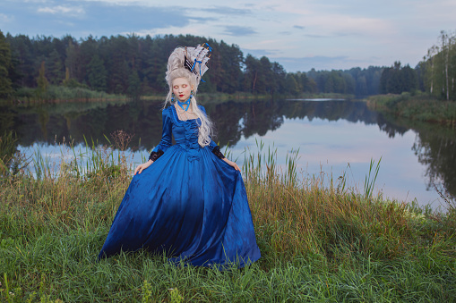 Renaissance princess with blonde hair on lake background.