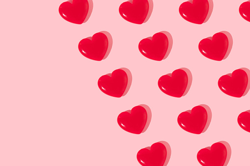 Valentines day creative pattern with bright red hearts on pastel pink background. 80s or 90s retro fashion aesthetic love concept. Minimal romantic idea with copy space.